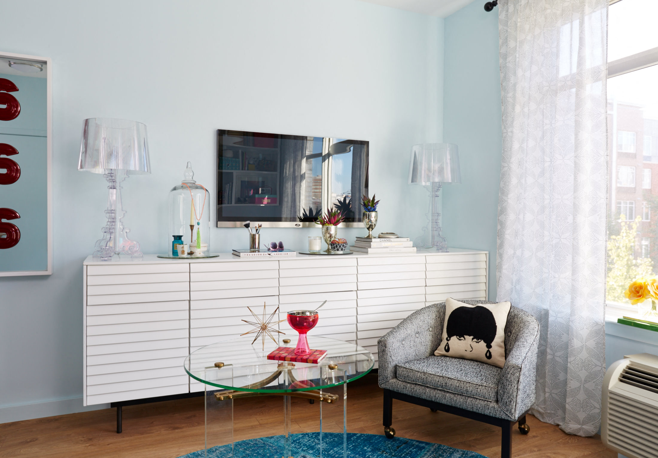 a living room with a chair and a dresser with a mirror