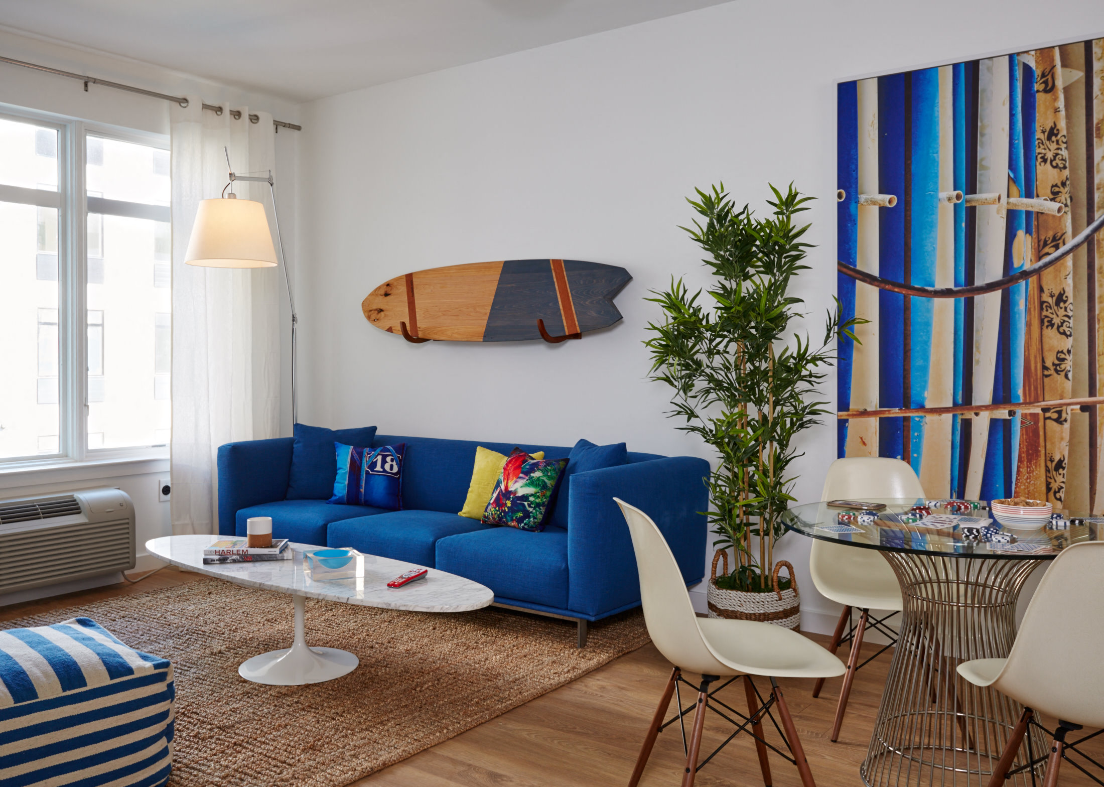 a living room with a blue couch and a surfboard on the wall