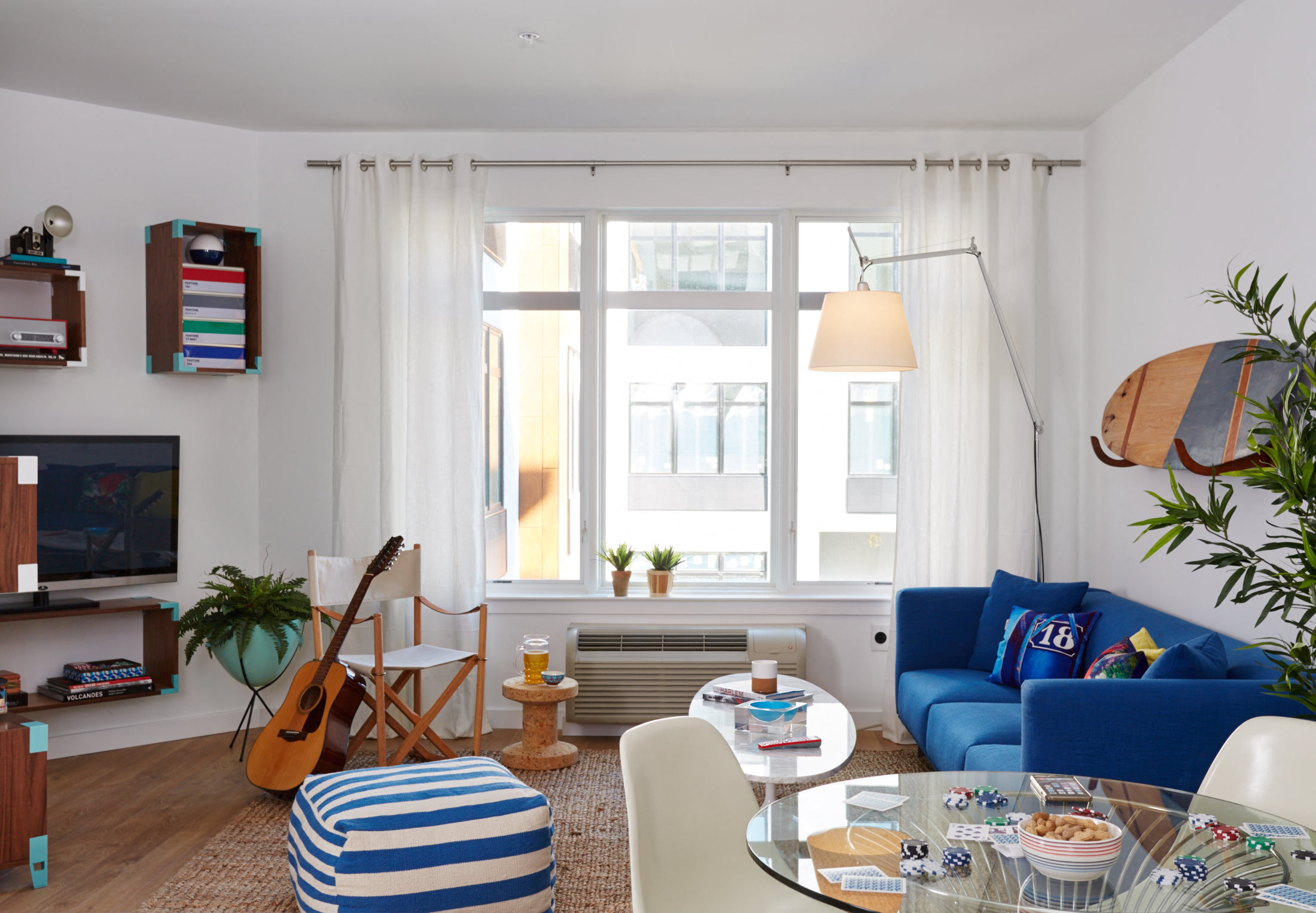 a living room with white walls and blue furniture and a window