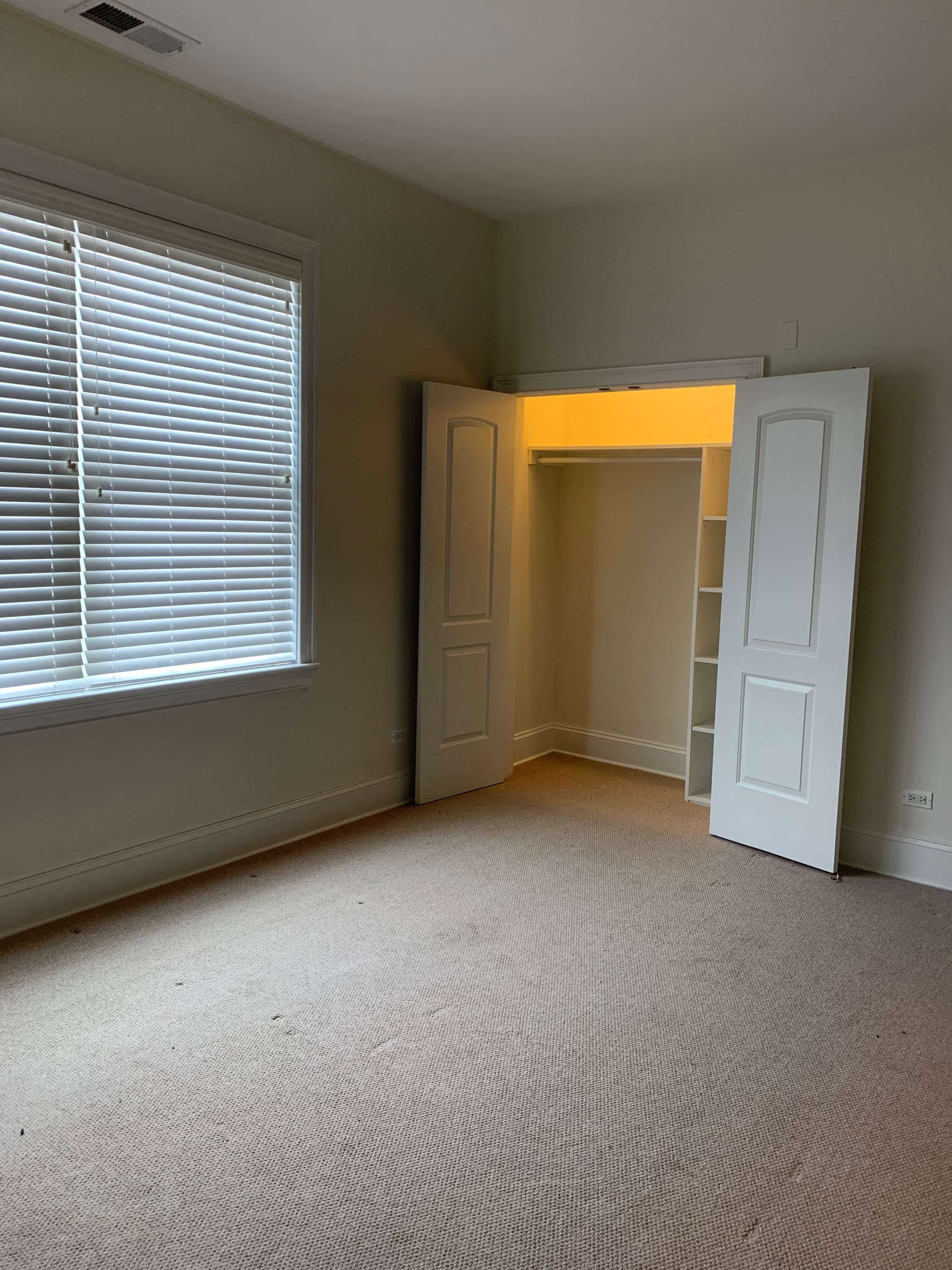 a bedroom with a large window and a door and a closet