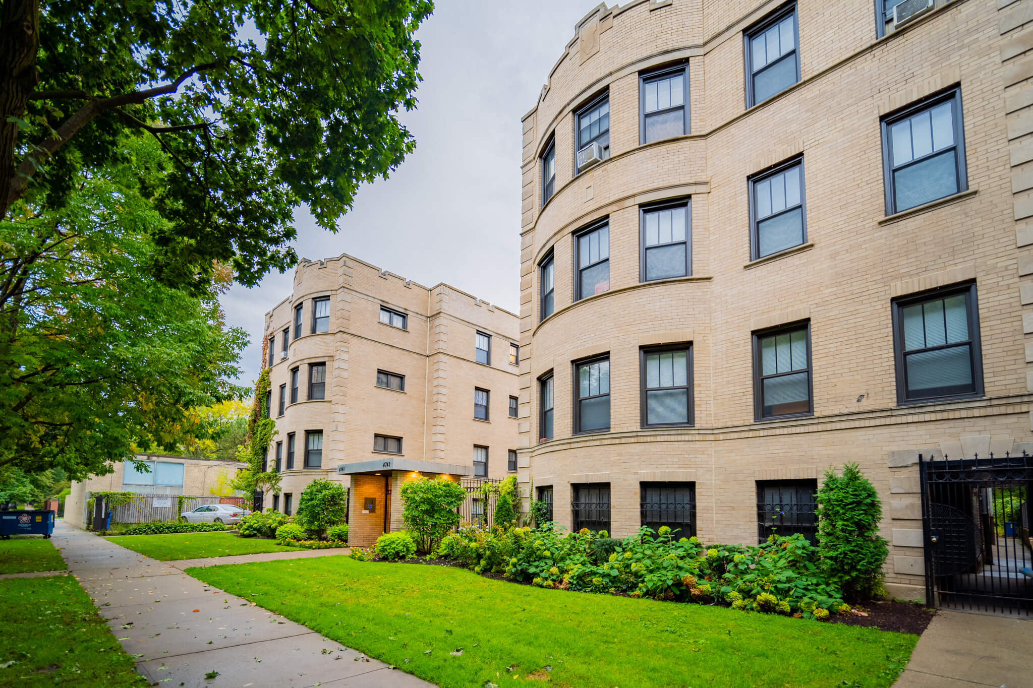 a sidewalk in front of a brick apartment building