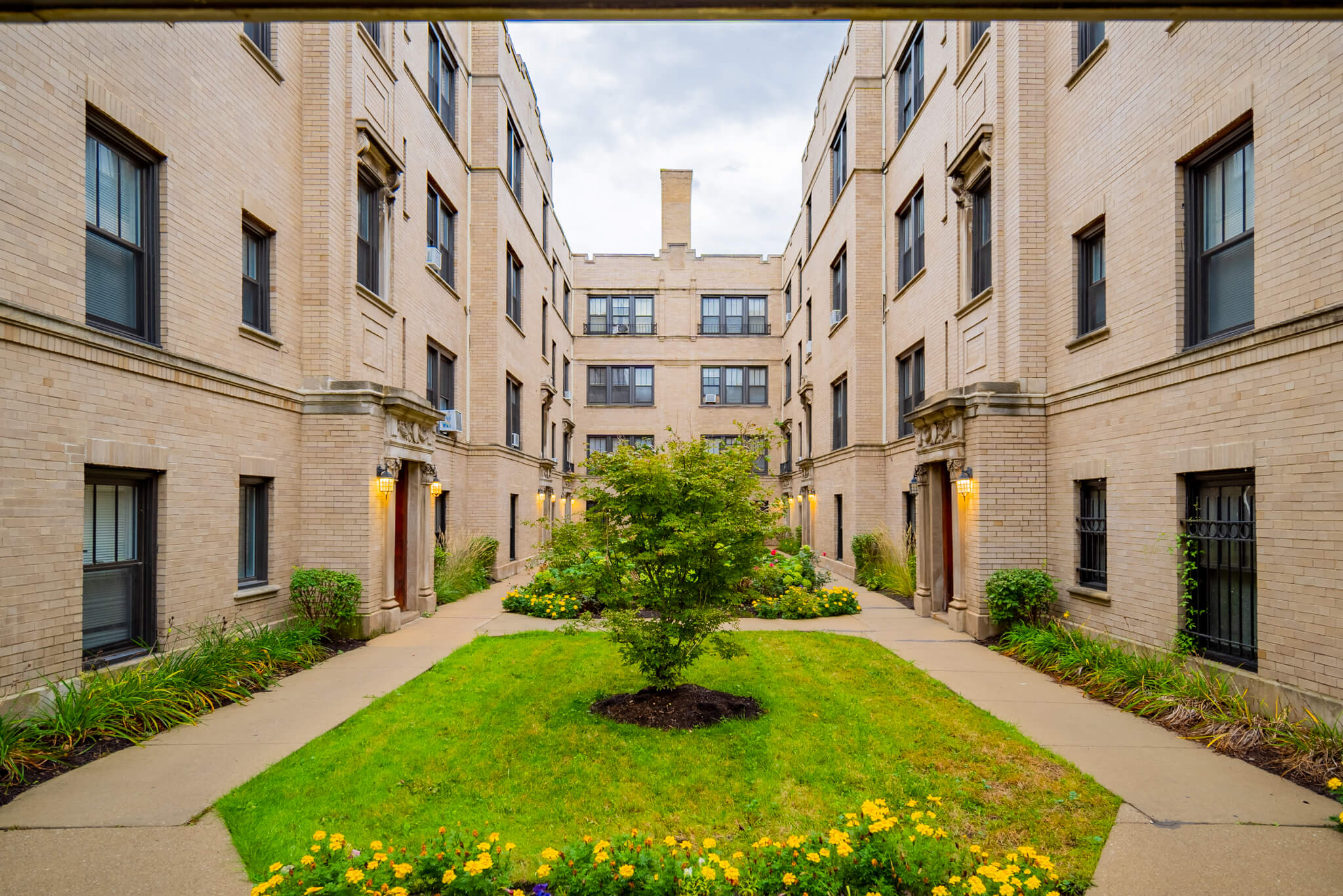 the courtyard of an apartment building with a tree in the middle