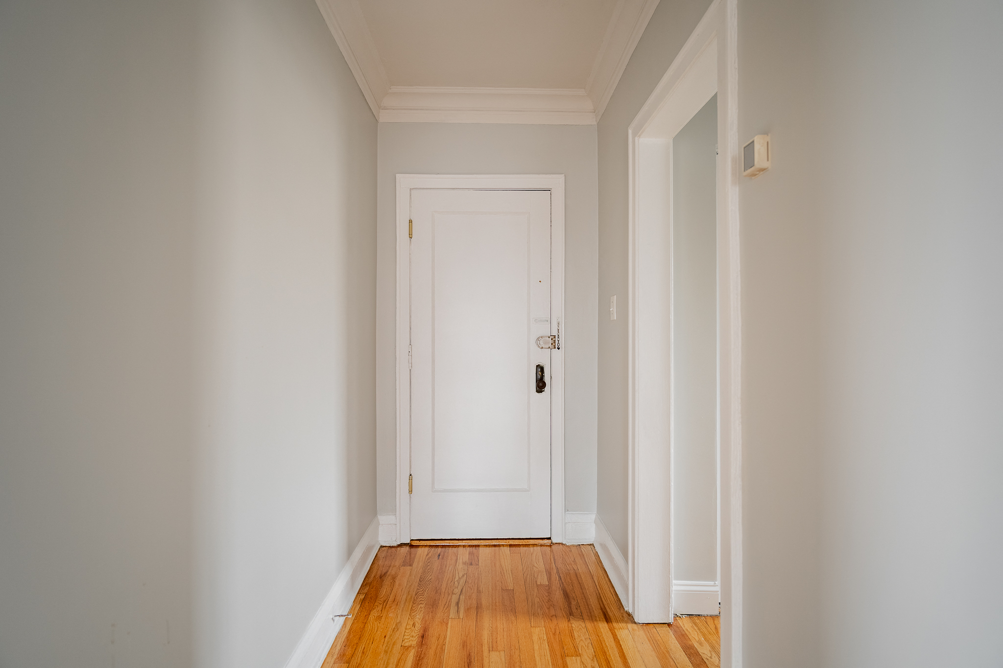 a hallway with a white door and wood floors