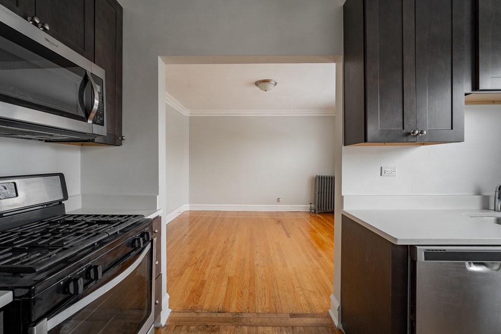 an empty kitchen with black appliances and wood floors