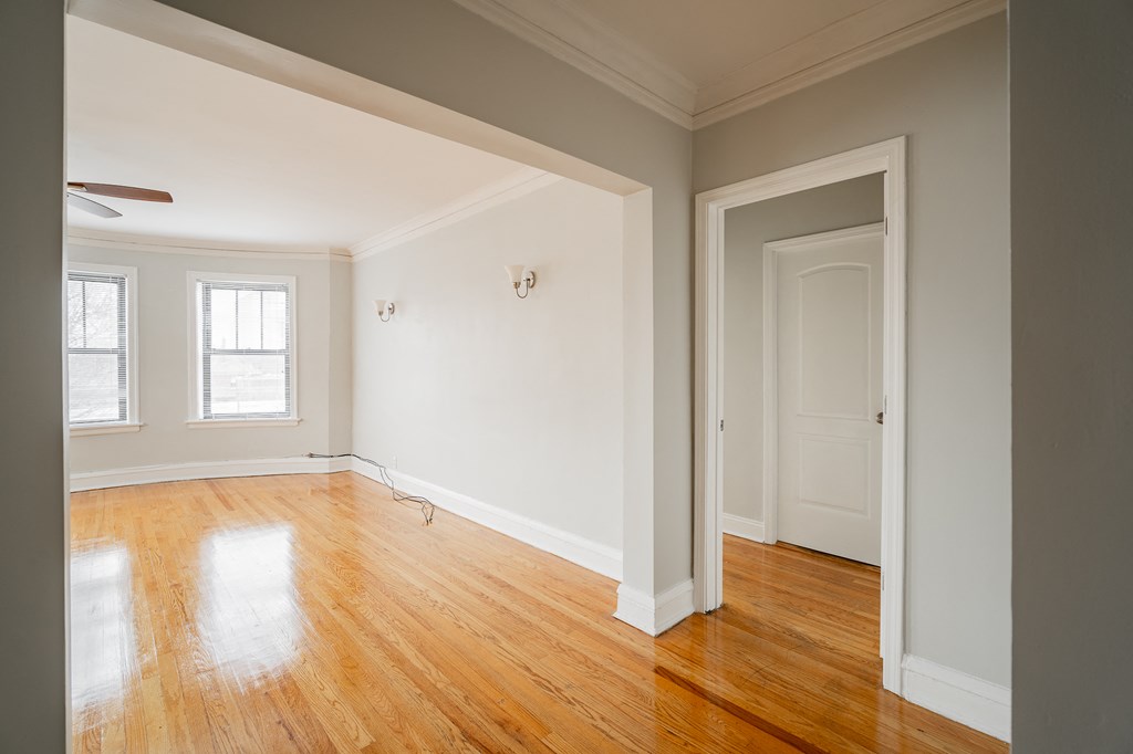 an empty living room with wood floors and white walls
