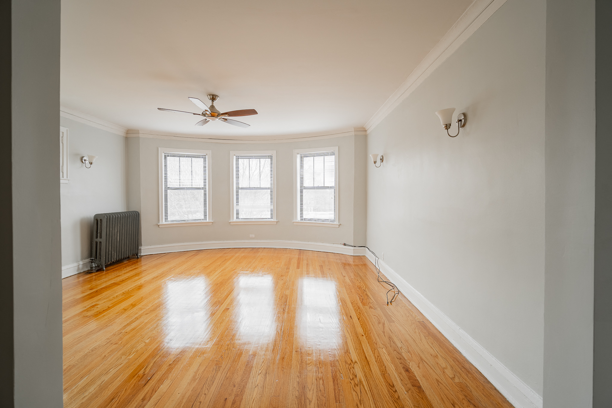 an empty living room with wood floors and a ceiling fan