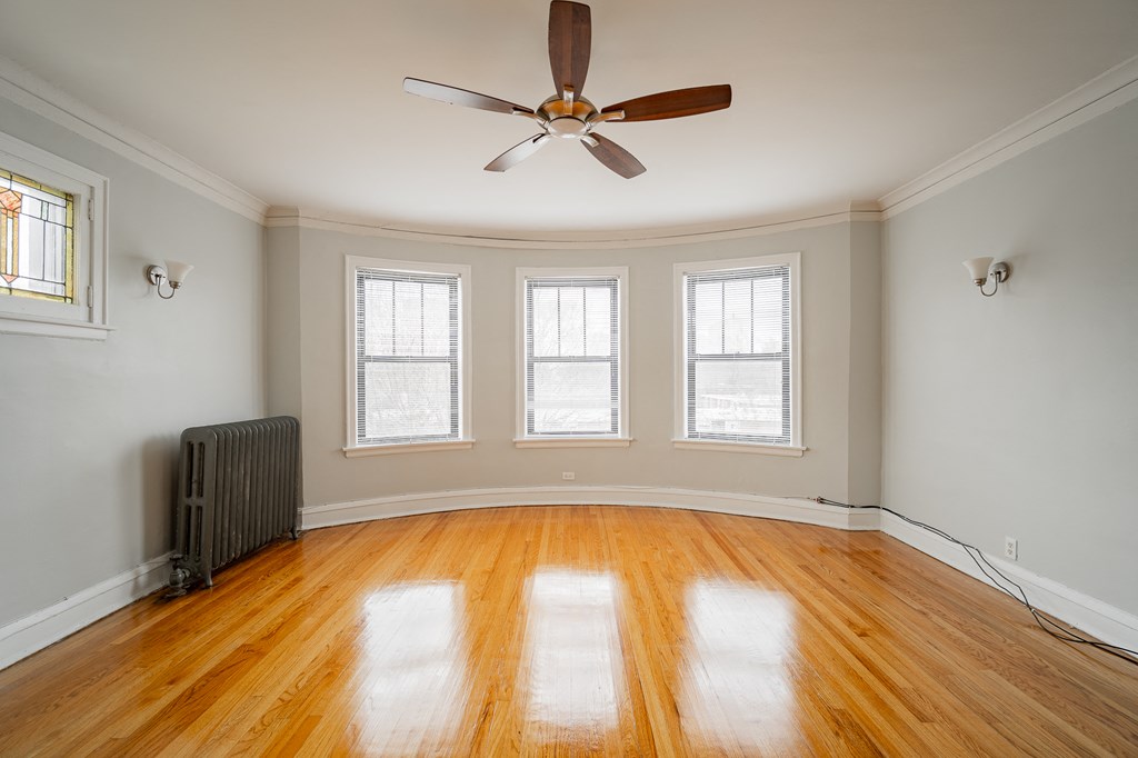 an empty room with a ceiling fan and three windows