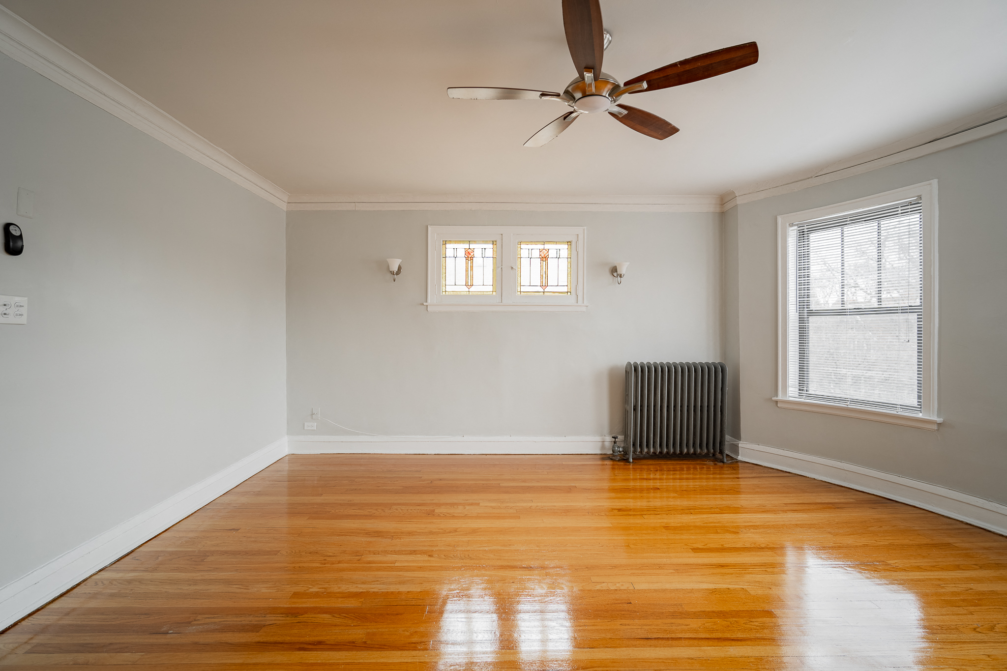an empty living room with wood floors and a ceiling fan