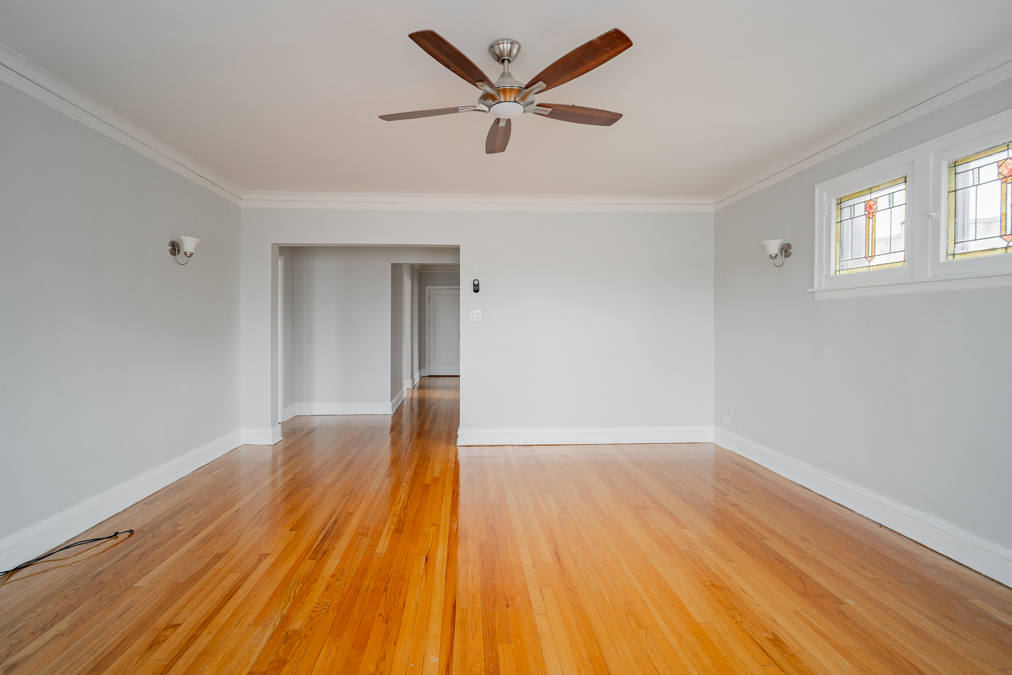 an empty living room with wood floors and a ceiling fan