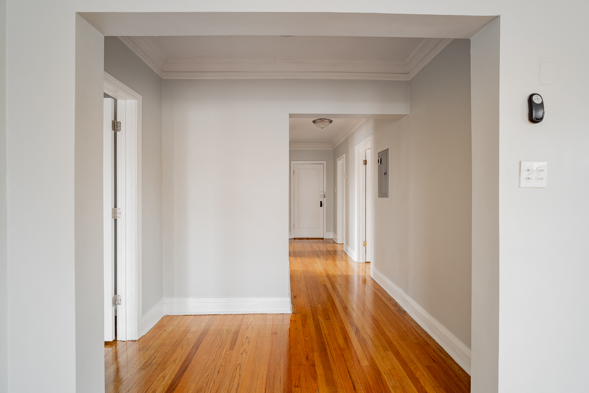 an empty hallway with white walls and wooden floors