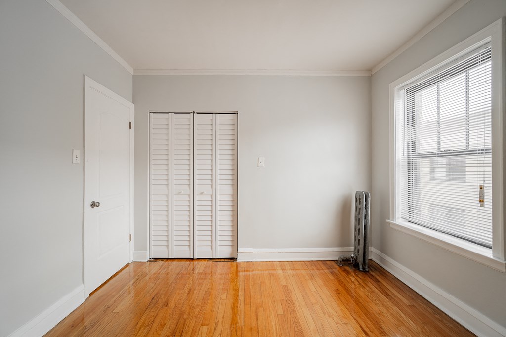 a living room with wood floors and white walls and a closet