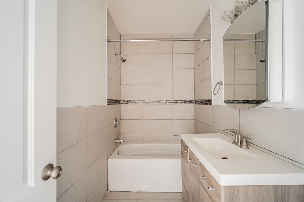 a small bathroom with a sink and a tub and a mirror