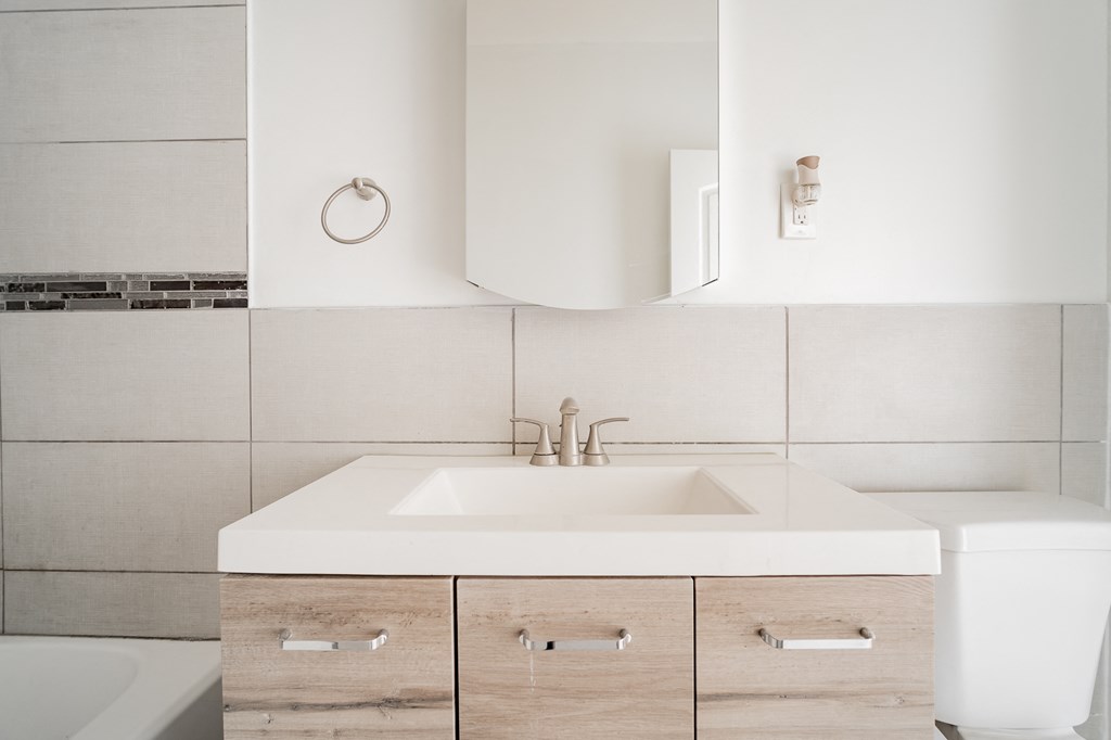 a white bathroom with wooden cabinets and a sink and a mirror