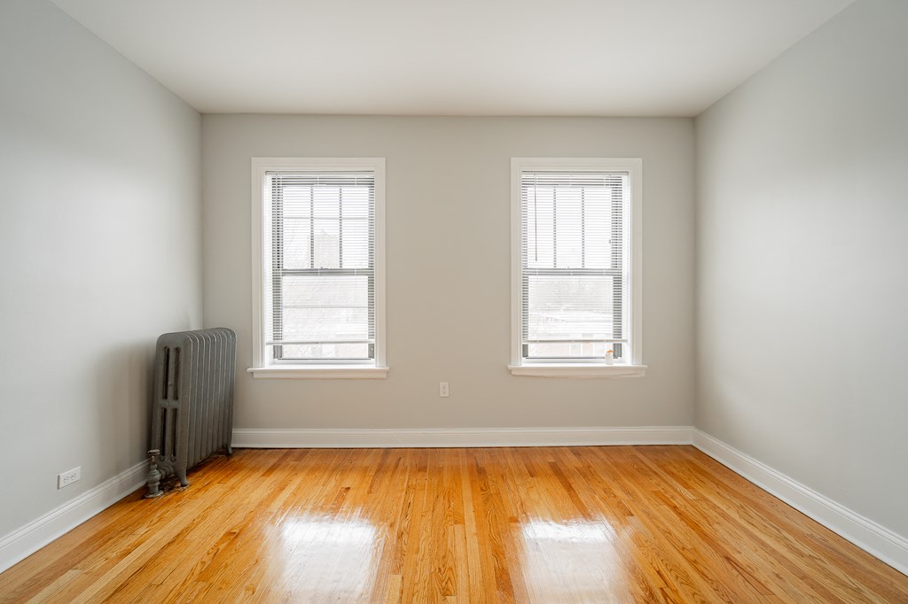 an empty room with a radiator and two windows