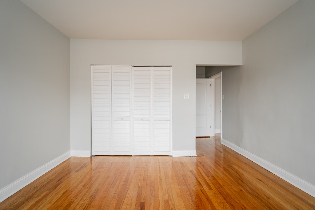 an empty living room with wood floors and a closet