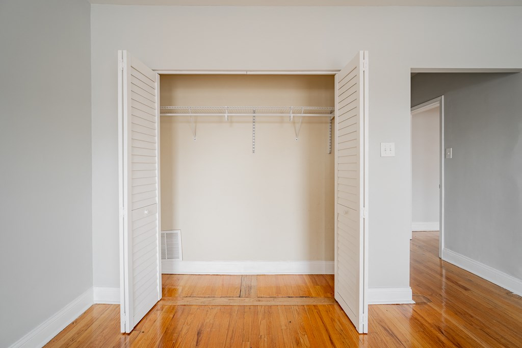 an empty closet with white shutters and wood floors