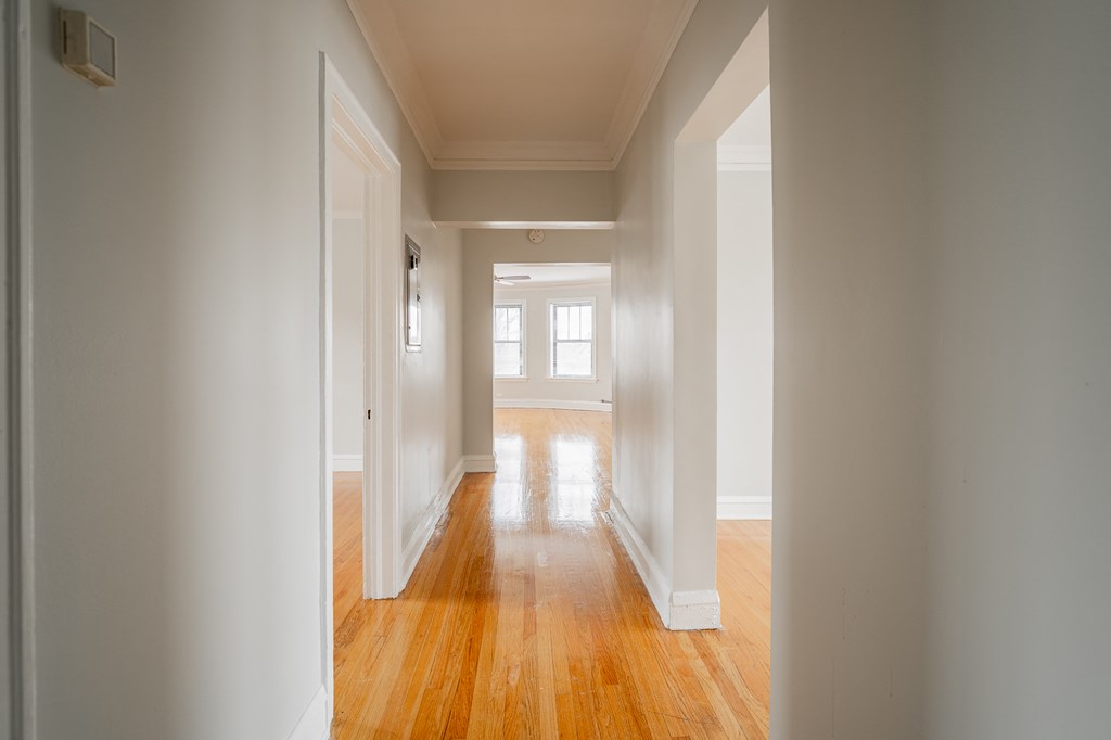 an empty hallway with white walls and wood floors
