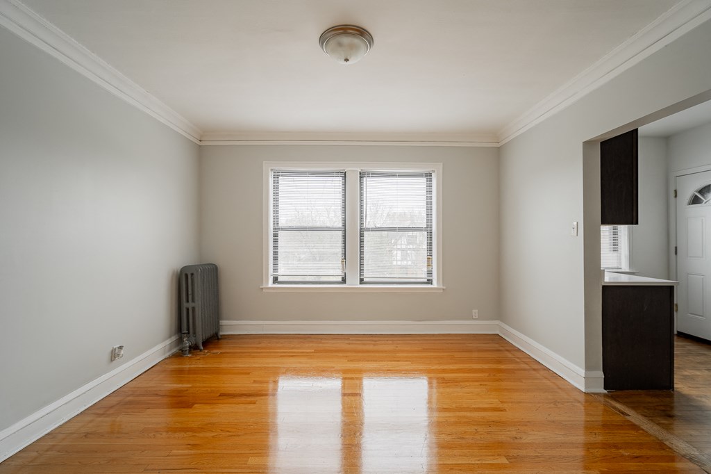 an empty living room with wood floors and a window