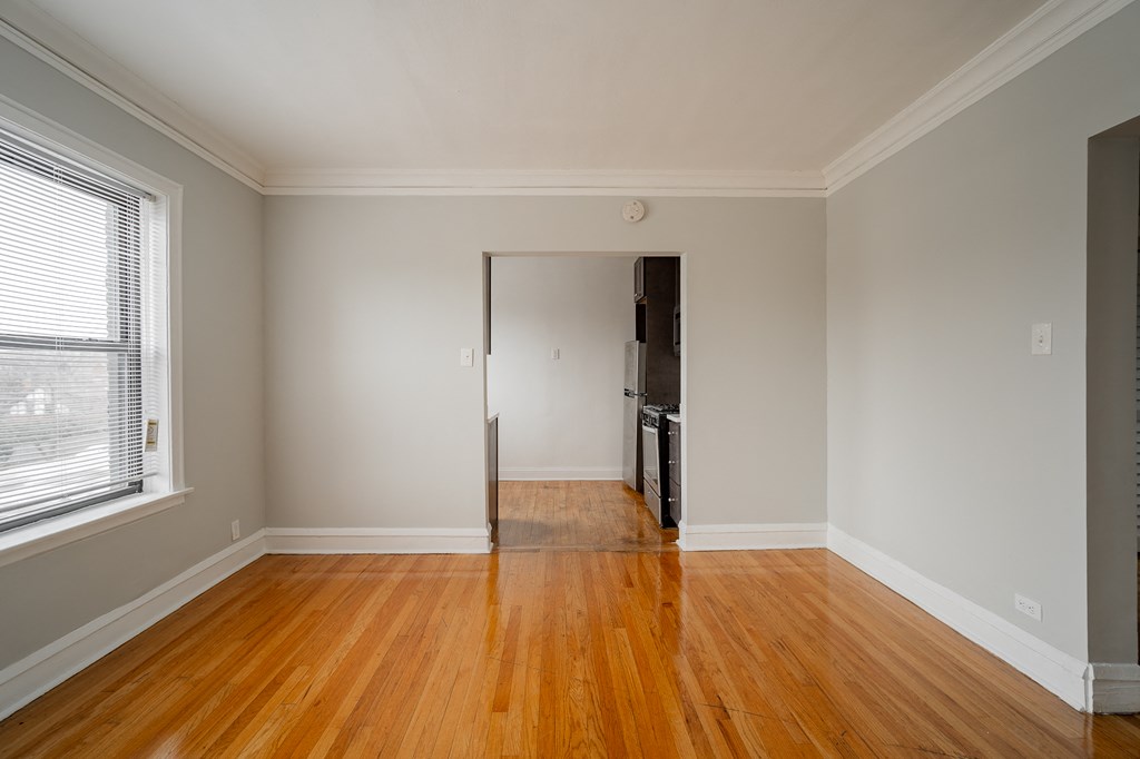 a living room with wood floors and a door to a kitchen
