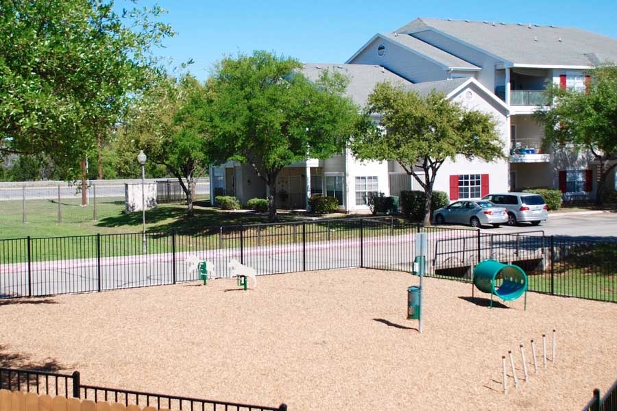 a fenced in dog park in front of an apartment building