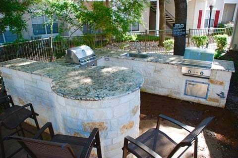 an outdoor kitchen with a stone wall and a grill