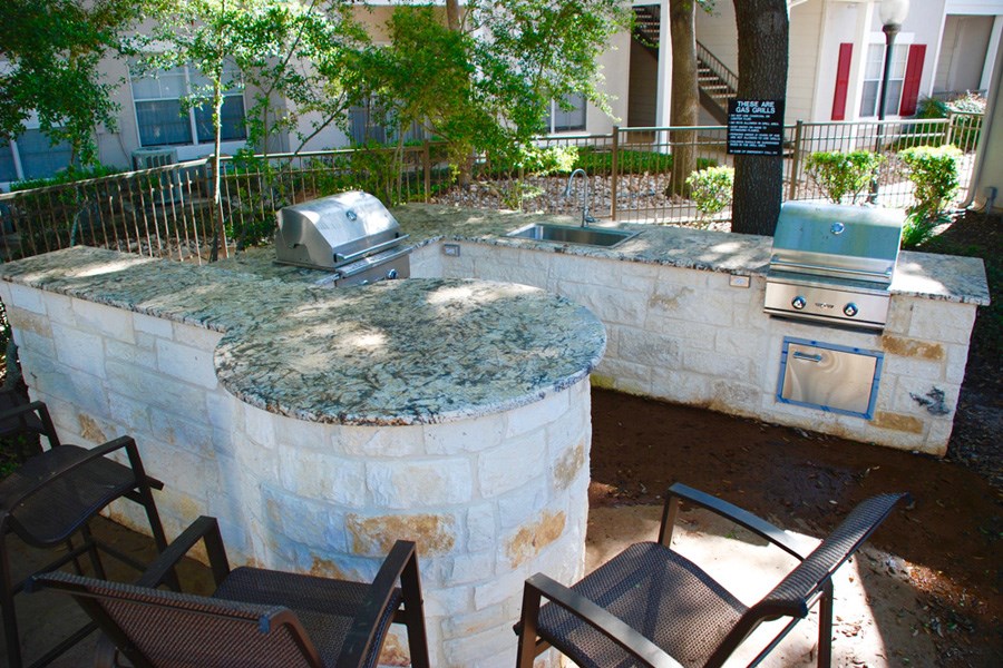 an outdoor kitchen with a stone wall and a grill