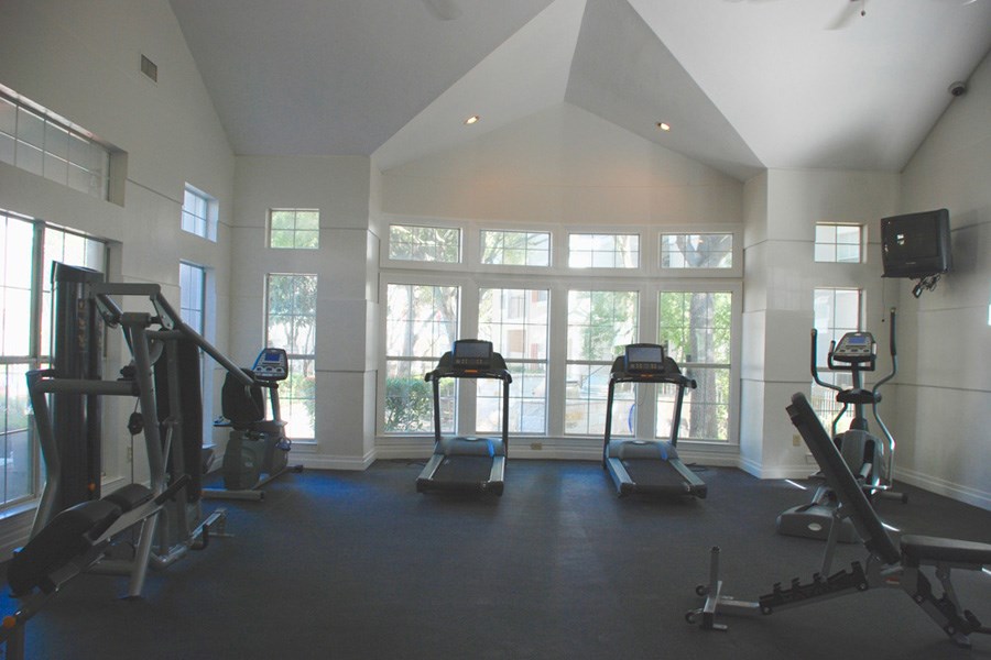 a gym with cardio equipment and windows in a building