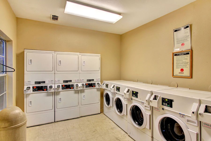 a laundry room with washers and dryers and a row of washing machines