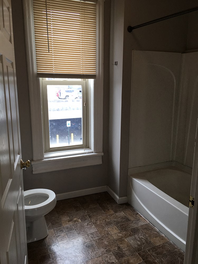 a bathroom with a window and a toilet and a tub