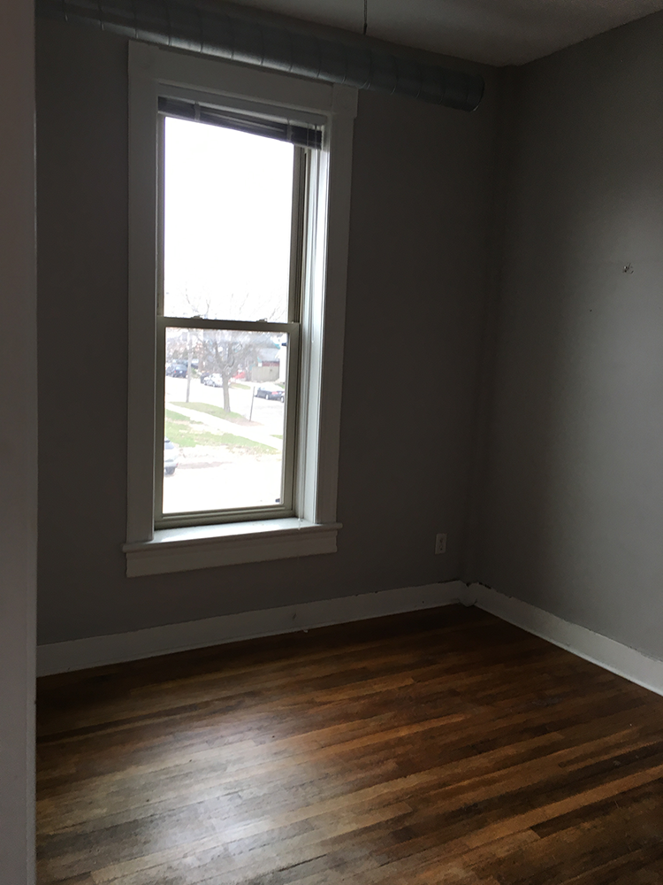 an empty room with a window and wooden floors
