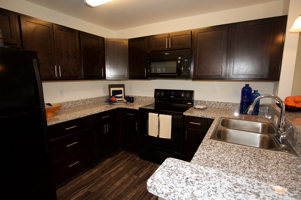 a kitchen with granite counter tops and dark wood cabinets