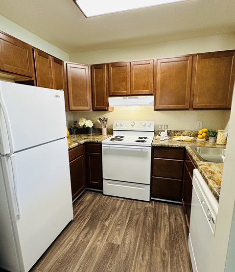 A kitchen with white appliances and brown cabinets.