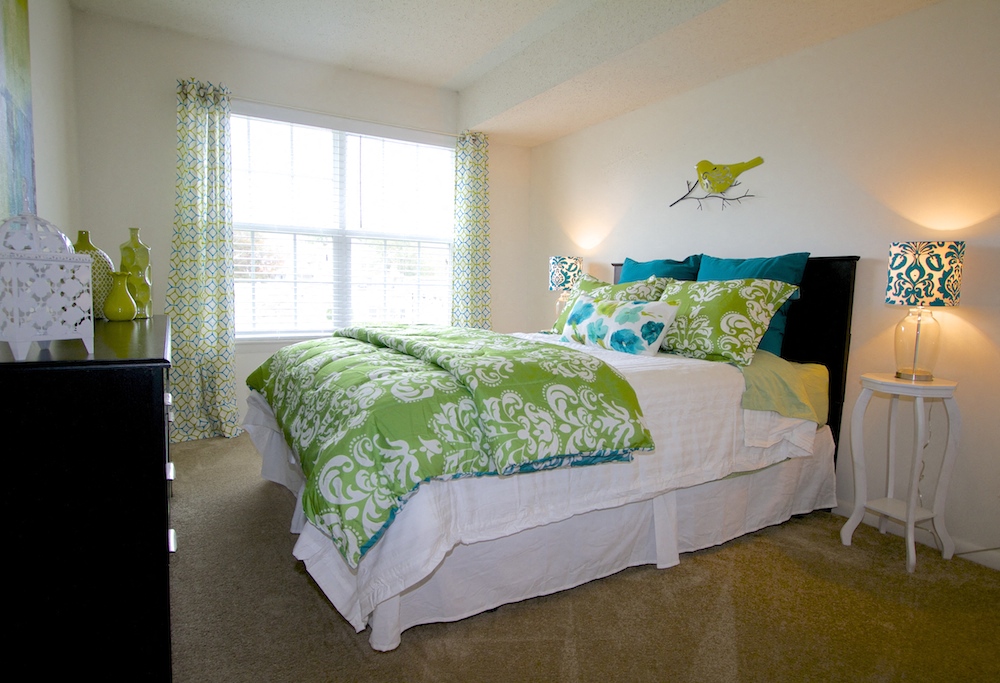 a bedroom with a bed with green and white comforter and pillows