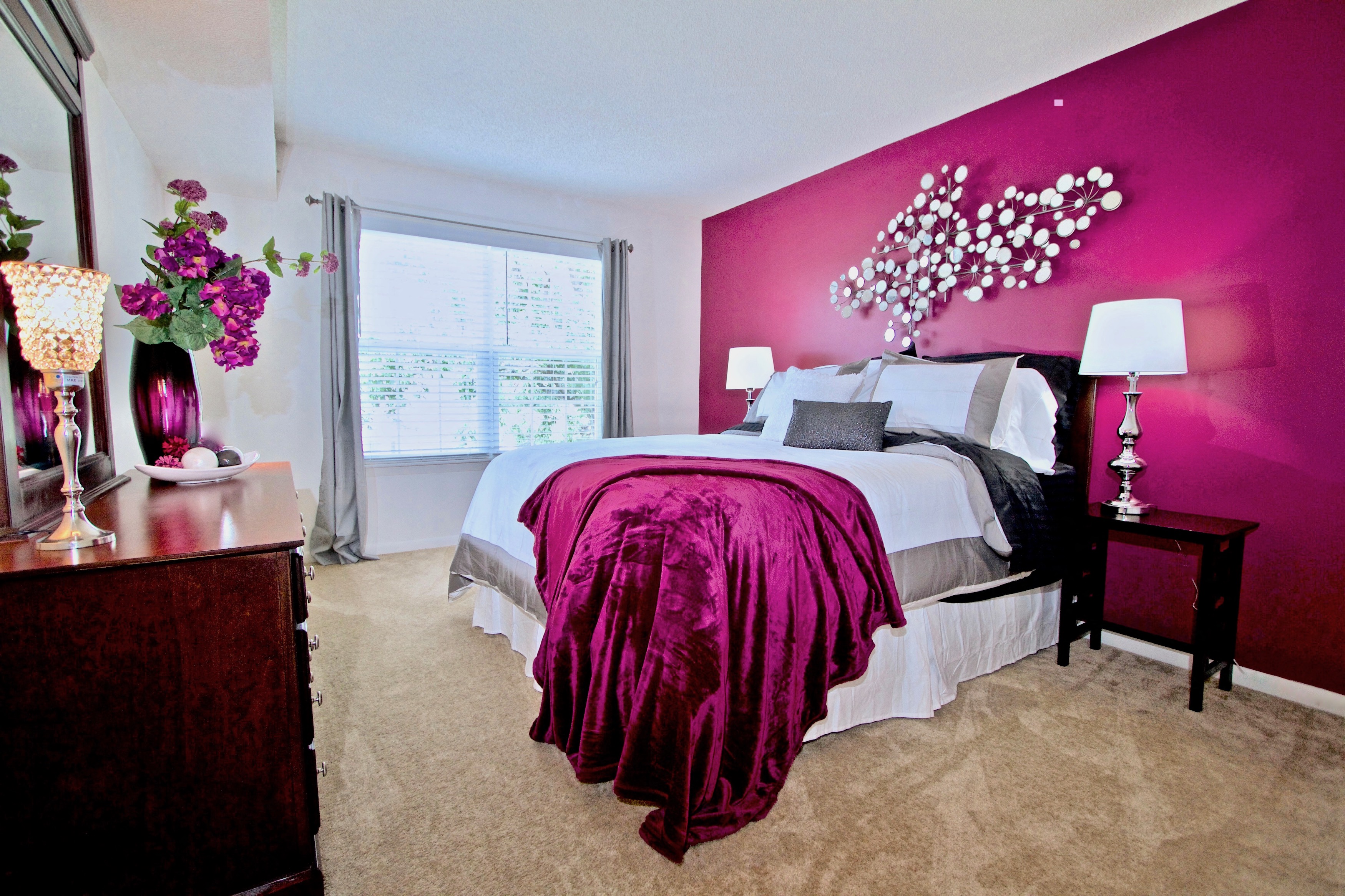 a bedroom with a pink accent wall and a white bed