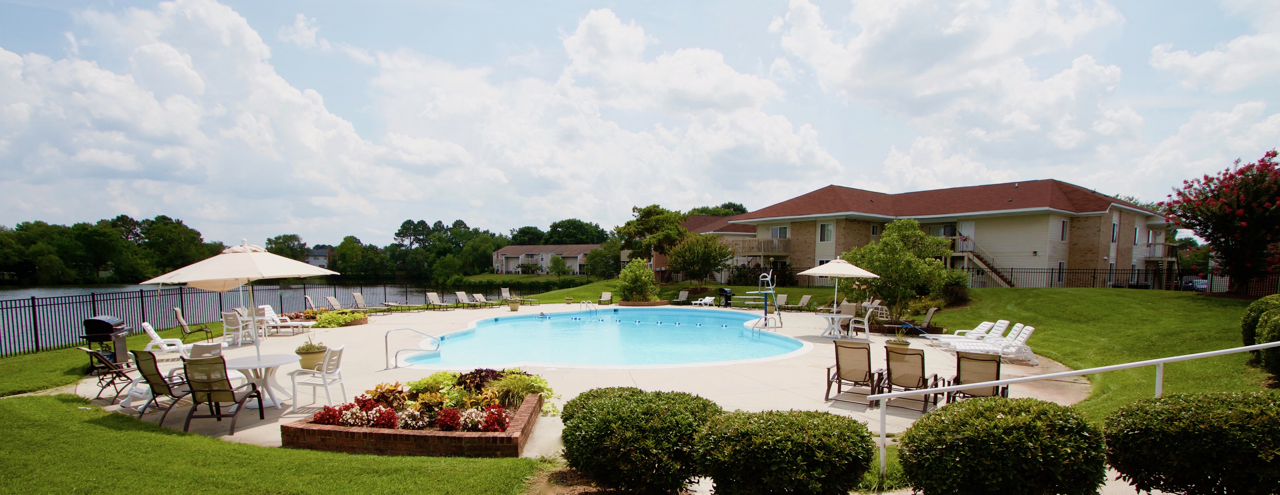 a swimming pool with chairs and umbrellas in front of a building