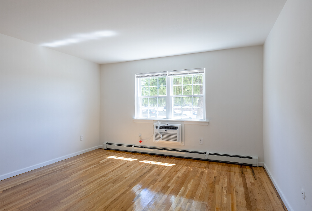 an empty room with wooden floors and a window