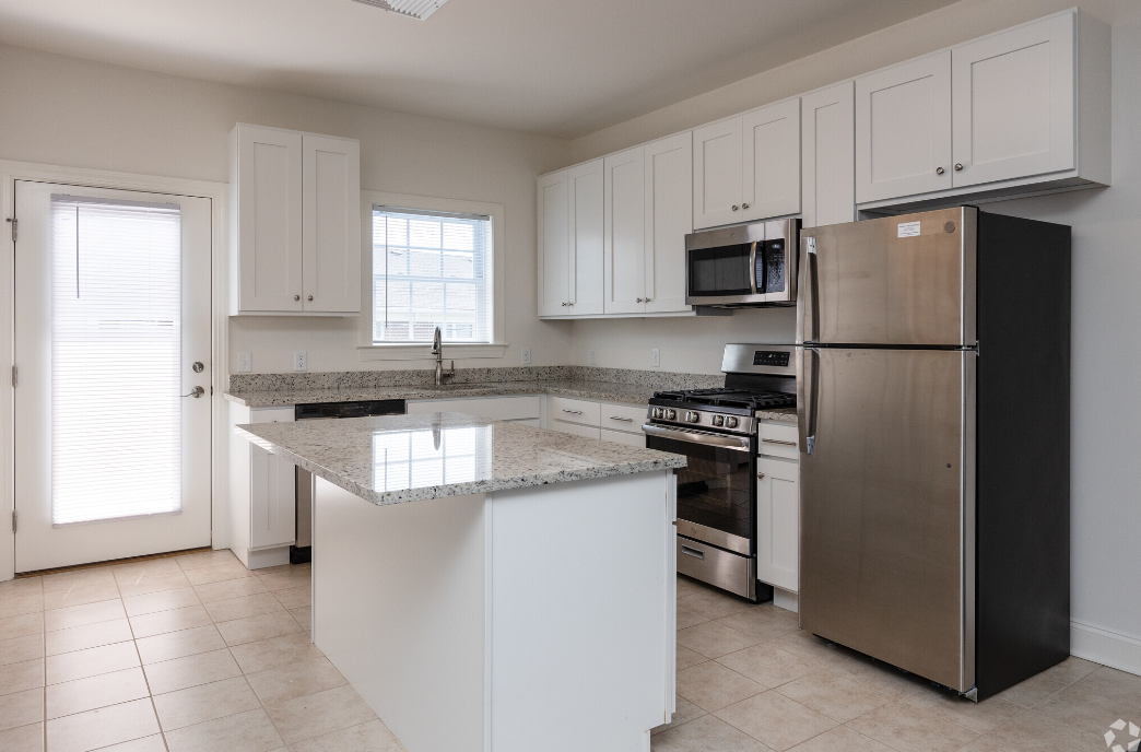 an empty kitchen with an island and stainless steel refrigerator