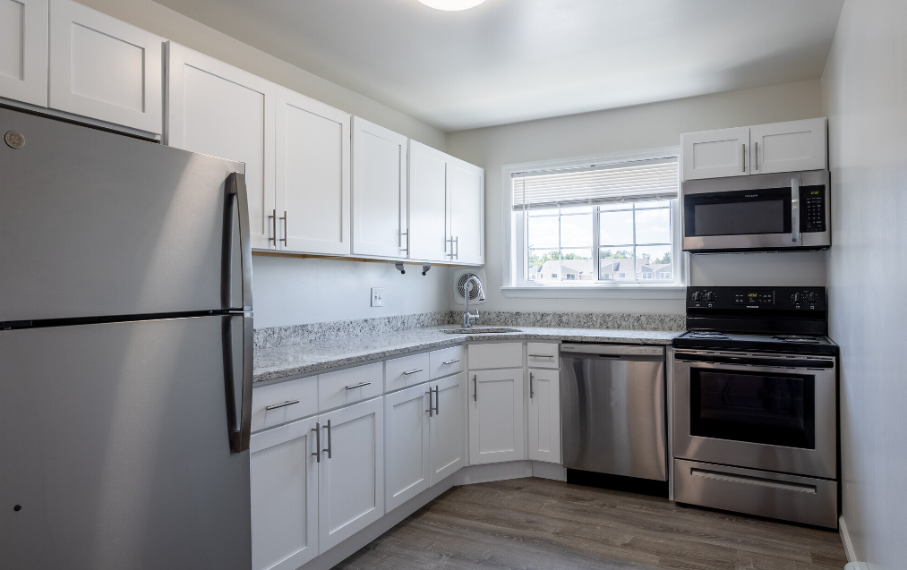 an empty kitchen with stainless steel appliances and white cabinets