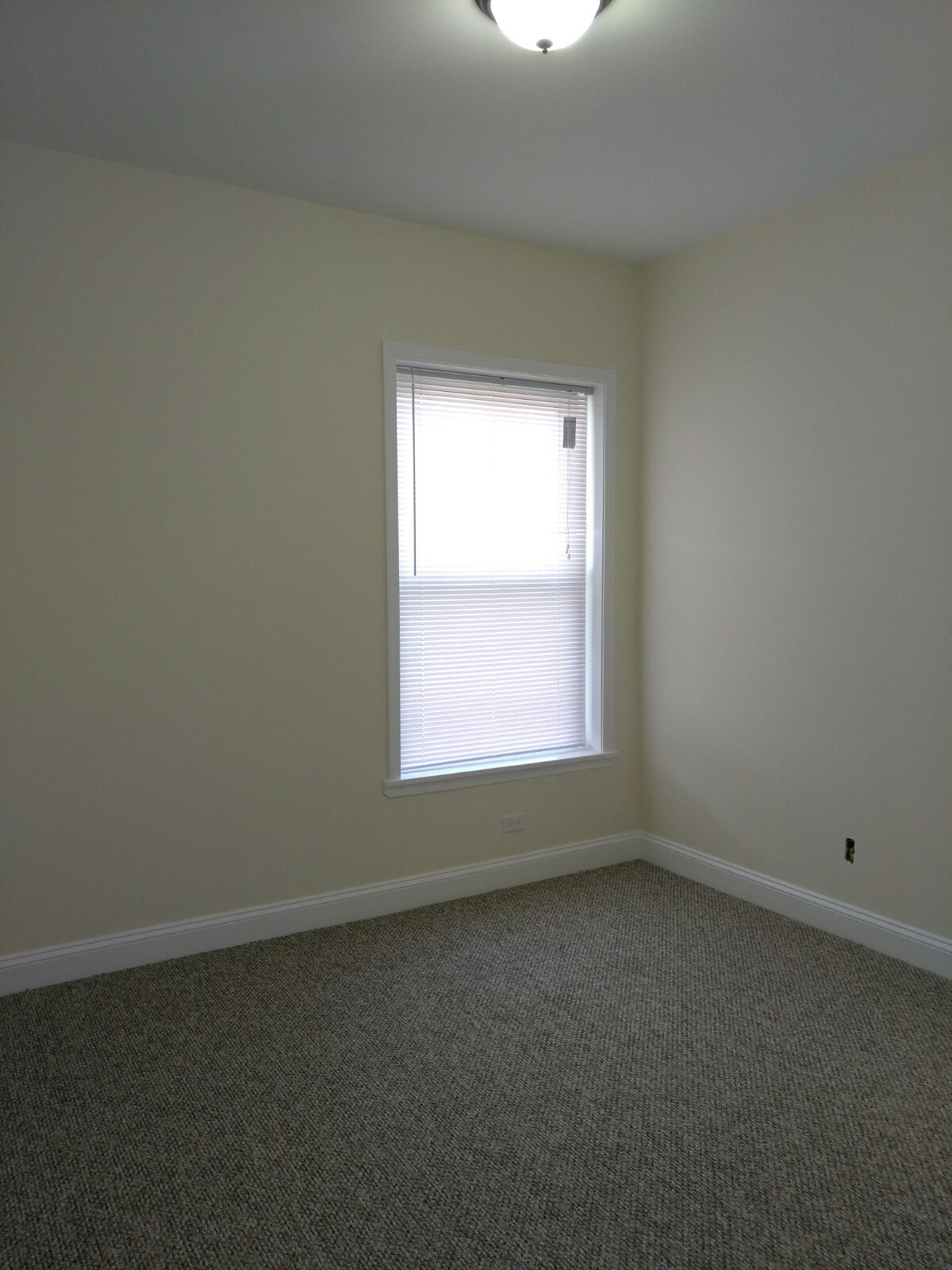 an empty room with a window and white walls