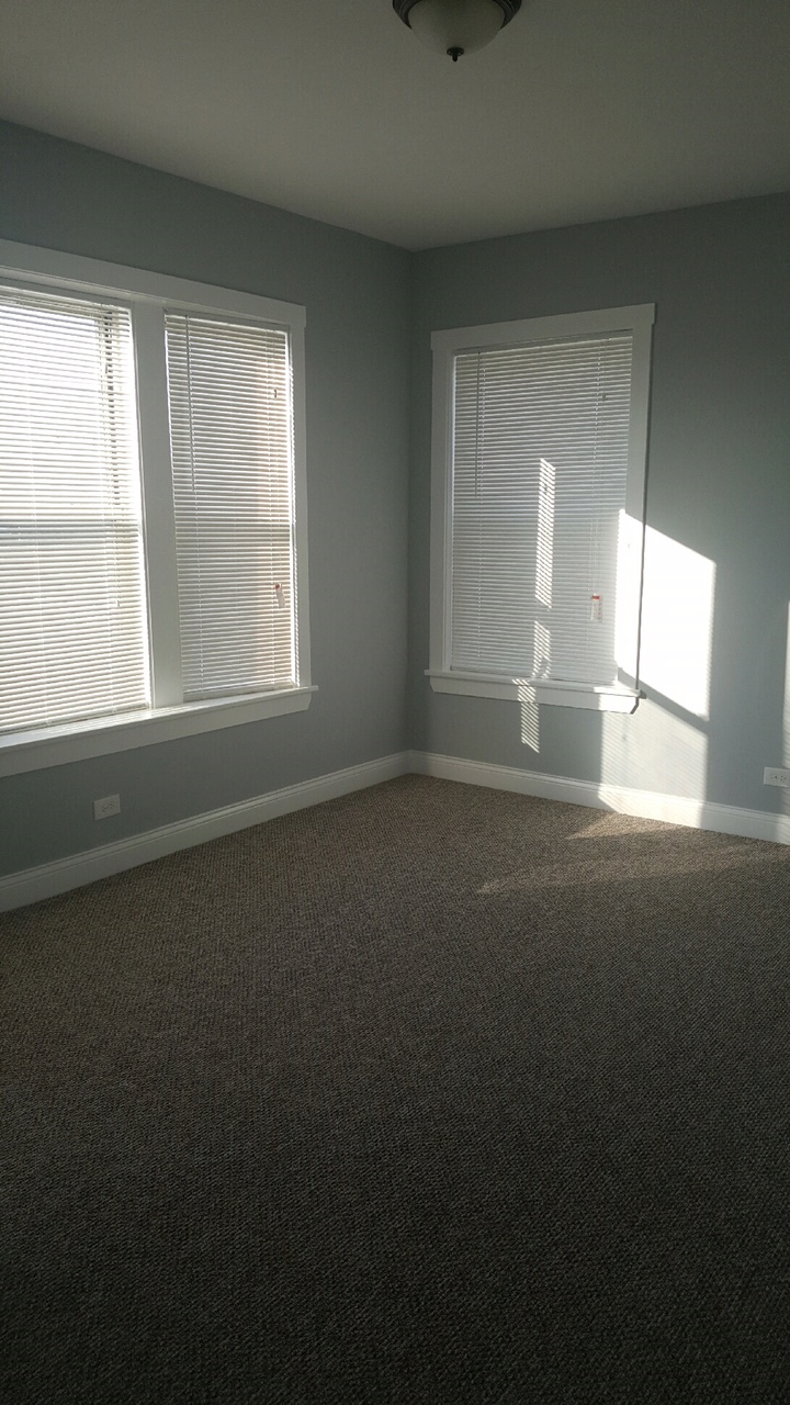 an empty room with two windows with blinds