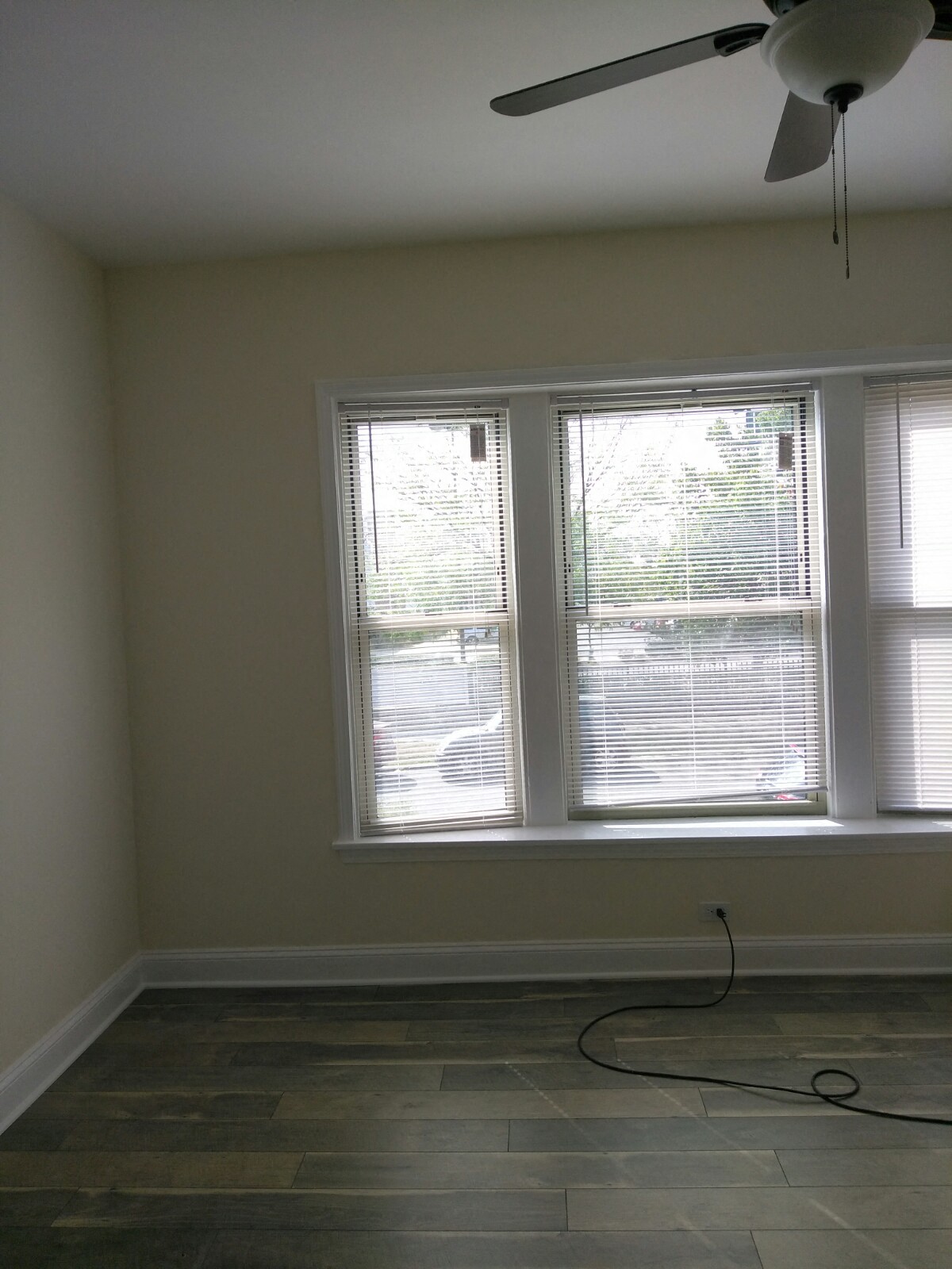 a living room with three windows and a ceiling fan