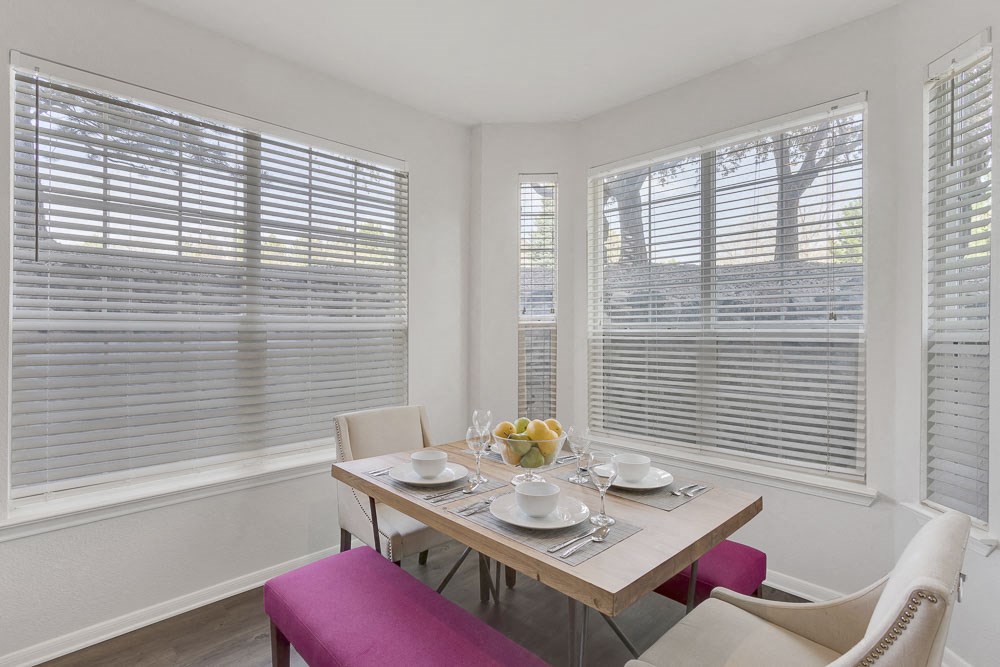 a dining room with three windows and a table with chairs