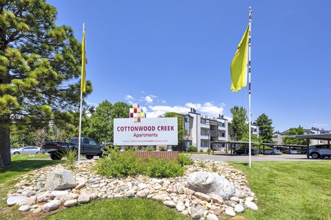 the entrance to stronghold creek apartments with flags and a sign