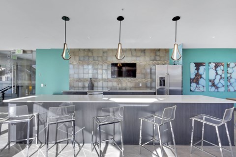 A modern kitchen with a long counter and bar stools.