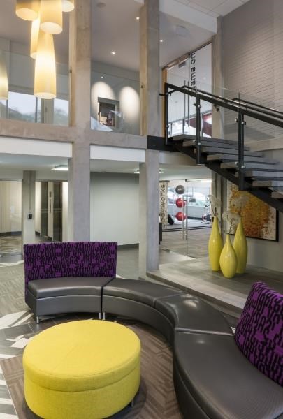 a lobby with a yellow table and chairs and a staircase