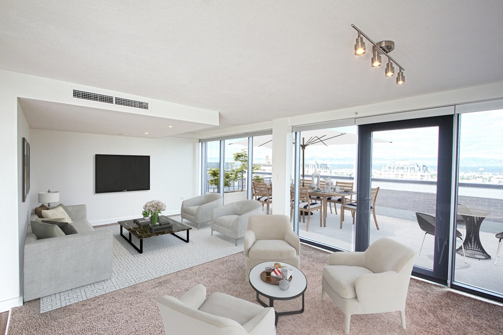 a living room with white couches and chairs and a tv on the wall