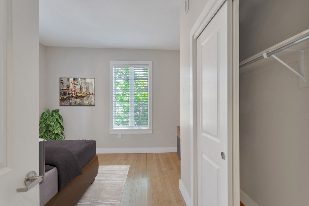 a bedroom with a large window and a door to a closet