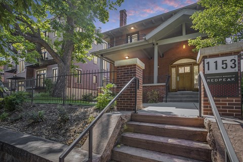 the front of a house with stairs and a sign in front of it