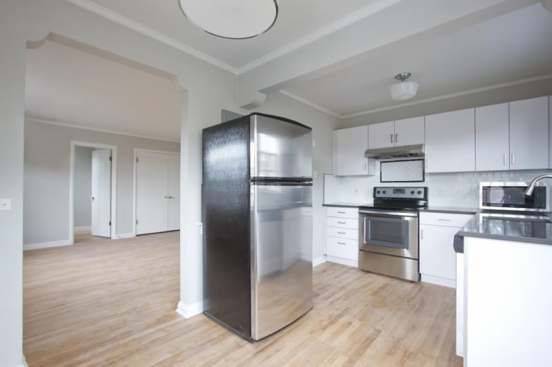 an empty kitchen with stainless steel appliances and white cabinets