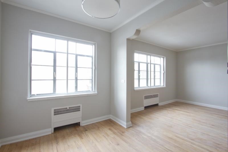 an empty living room with a wood floor and two windows
